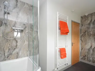 a bathroom with a shower with orange towels on the wall at Berwyn View in Welshpool