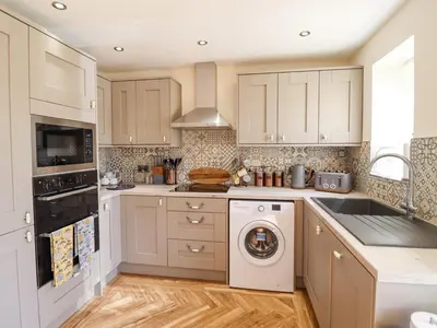 a kitchen with white cabinets and a washer and dryer at Varley Villa in Newtown