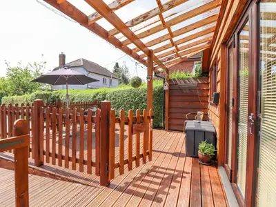 a wooden deck with an umbrella and a fence at Varley Villa in Newtown