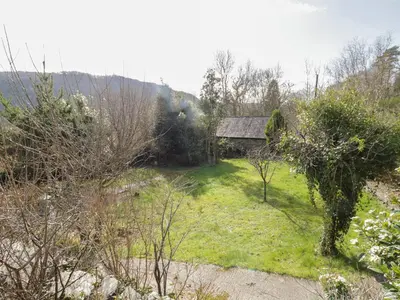 a garden with a building in the middle of a field at The Old Smithy Cottage in Blaenau-Ffestiniog