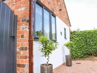 a brick building with two potted plants in front of a door at Little Oakleigh in Llanymynech