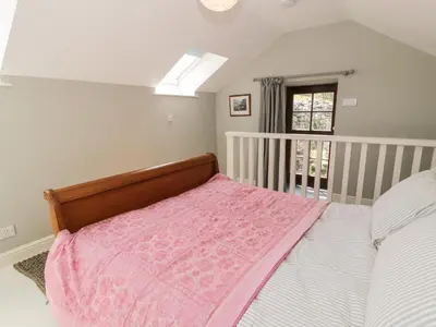 a bedroom with a bed with a pink blanket at Gelli Bach at Gelli Las in Llanbedr