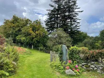 a garden with a fence and flowers and a tree at Gelli Bach at Gelli Las in Llanbedr