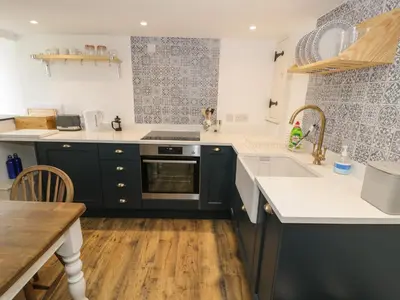 a kitchen with blue cabinets and white counter tops at Gelli Bach at Gelli Las in Llanbedr