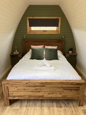 a bedroom with a large bed with a window at Delor - Bryntalch Glamping Pods in Montgomery