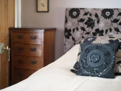 a bedroom with a bed with a pillow and a dresser at Galeri Harlech Townhouse in Harlech