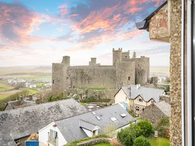 a castle in the middle of a town with roofs at Galeri Harlech Townhouse in Harlech