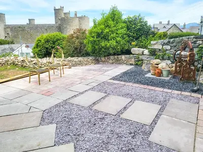 a stone patio with benches and a castle in the background at Galeri Harlech Townhouse in Harlech
