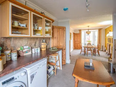 a kitchen with wooden cabinets and a table and a dining room at Galeri Harlech Townhouse in Harlech