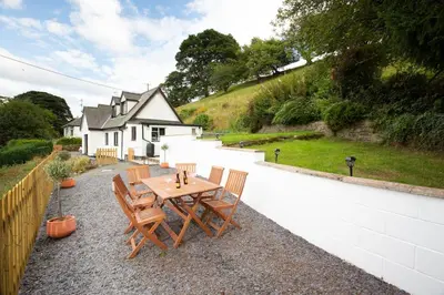 a wooden table and chairs on a patio at Hillside Cottage, countryside views near Llangollen in Corwen
