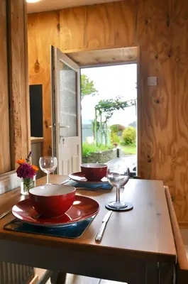 a table with two bowls and wine glasses on it at Spacious heated Yurt with Hot tub, 5 mins to beach in Bow Street