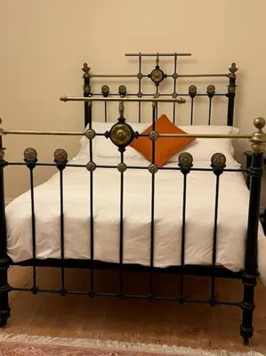 a bed with a black frame and white sheets at Cae Nest Hall in Llanbedr