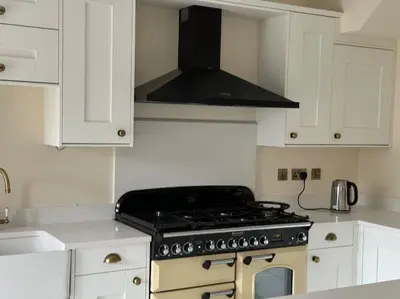 a stove top oven in a kitchen with white cabinets at Cae Nest Hall in Llanbedr