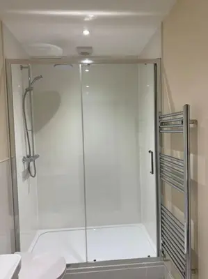 a shower with a glass door in a bathroom at Cae Nest Hall in Llanbedr