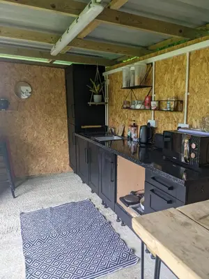 a kitchen with black cabinets and a counter top at Stay Wild Retreats 'Glamping Pods and Tents' in Wrexham