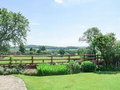 a wooden fence in front of a field with flowers at Barnleigh in Ludlow
