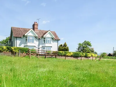 a white house with a fence in a field at Barnleigh in Ludlow