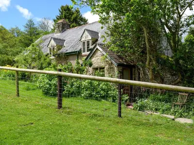 an old house with a fence in front of it at Lower Goytre Farmhouse in Llanvair Waterdine