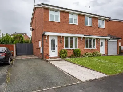 a brick house with a car parked in the driveway at Cheerful and modern one bedroom home with parking - Pass the Keys in Shrewsbury