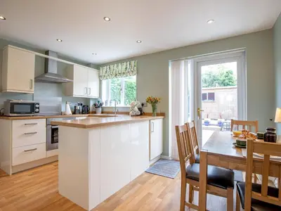 a kitchen with white cabinets and a table and a dining room at Cheerful and modern one bedroom home with parking - Pass the Keys in Shrewsbury