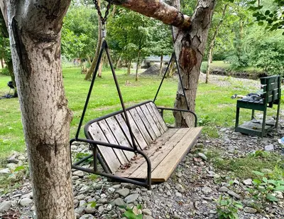 a swing hanging from a tree in a park at River View Glamping in Llandovery