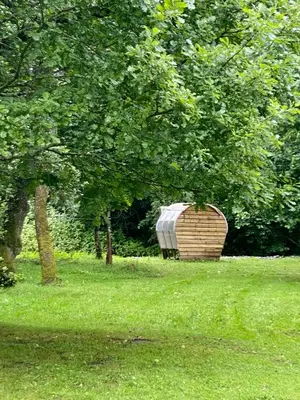 a barrel sitting in the grass near some trees at River View Glamping in Llandovery