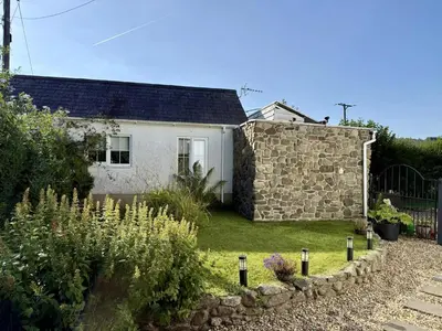 a white house with a stone wall and a garden at Daffodil House , West Wales in Llandovery