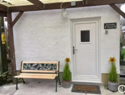 a wooden bench sitting in front of a white door at Daffodil House , West Wales in Llandovery