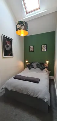 a bedroom with a large bed with a green wall at Cosy Spring Cottage at Pen Y Coed Hall in Dolgellau