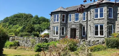 an old stone house with a stone wall at Cosy Spring Cottage at Pen Y Coed Hall in Dolgellau