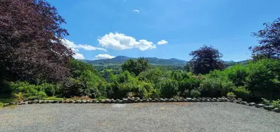 a gravel driveway with a stone wall in a garden at Cosy Spring Cottage at Pen Y Coed Hall in Dolgellau