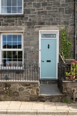 a stone building with a blue door and a window at Glasfryn Cottage Dolgellau in Dolgellau