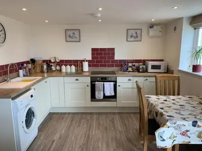 a kitchen with a table and a sink and a stove at The Granary at Pentregaer Ucha, tennis court & lake. in Oswestry