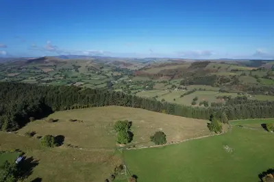 an aerial view of a green field with trees at The Granary at Pentregaer Ucha, tennis court & lake. in Oswestry