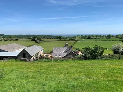 a house in the middle of a green field at The Granary at Pentregaer Ucha, tennis court & lake. in Oswestry