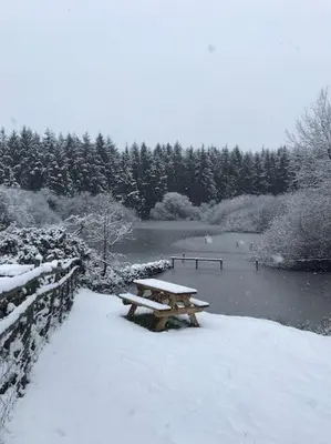 a picnic table in the snow next to a river at The Granary at Pentregaer Ucha, tennis court & lake. in Oswestry