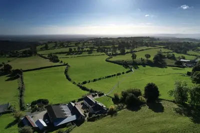 an aerial view of a field with houses and trees at The Granary at Pentregaer Ucha, tennis court & lake. in Oswestry