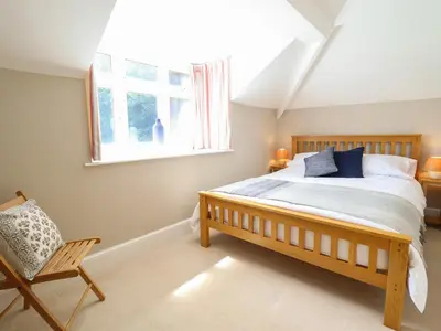 a bedroom with a bed and a window and a chair at Bodowen Coach House in Barmouth