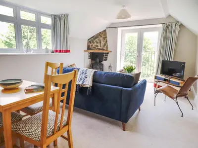 a living room with a blue couch and a table at Bodowen Coach House in Barmouth