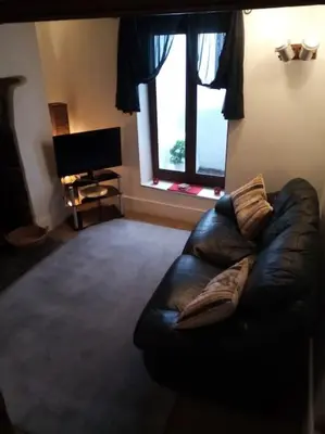 a leather couch in a living room with a window at Bridge View Victorian Townhouse Central Aberystwyth Sleeps 6 in Aberystwyth