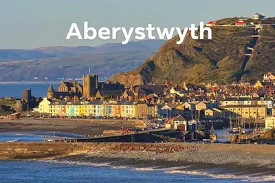 a town on the beach with a mountain in the background at Bridge View Victorian Townhouse Central Aberystwyth Sleeps 6 in Aberystwyth