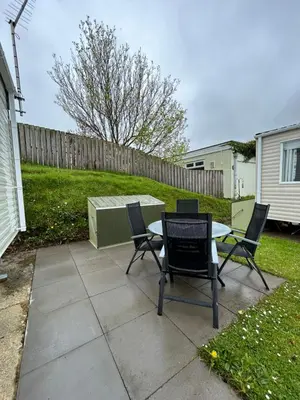 a patio with a table and chairs in a yard at Delightful 2 bedroom Caravan, Pencnwc, New Quay in Cross Inn