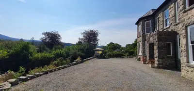 an empty road in front of a stone building at Large Mach Apartment at Pen Y Coed Hall in Dolgellau