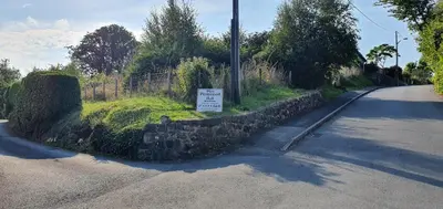 a sign on a stone wall next to a road at Large Mach Apartment at Pen Y Coed Hall in Dolgellau