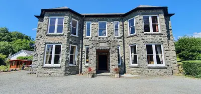 an old stone house with a front door at Large Mach Apartment at Pen Y Coed Hall in Dolgellau