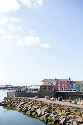 a harbor with rocks in the water and buildings at John Lewis Apartment in Aberaeron