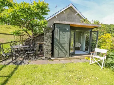 a small cottage with a table and chairs in the yard at Bryniau Bychain Cottage in Machynlleth