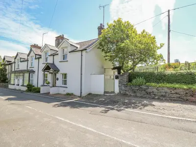 a white house on the side of a street at Bryniau Bychain Cottage in Machynlleth