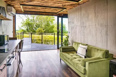 a living room with a green couch and a balcony at Rusty Boathouse in Llanarth