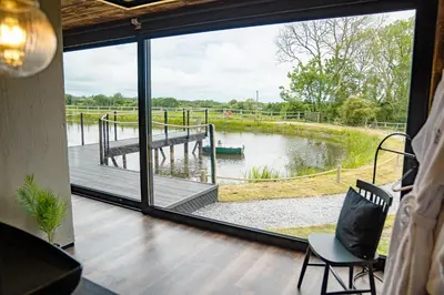 a room with a large window looking out at a lake at Rusty Boathouse in Llanarth